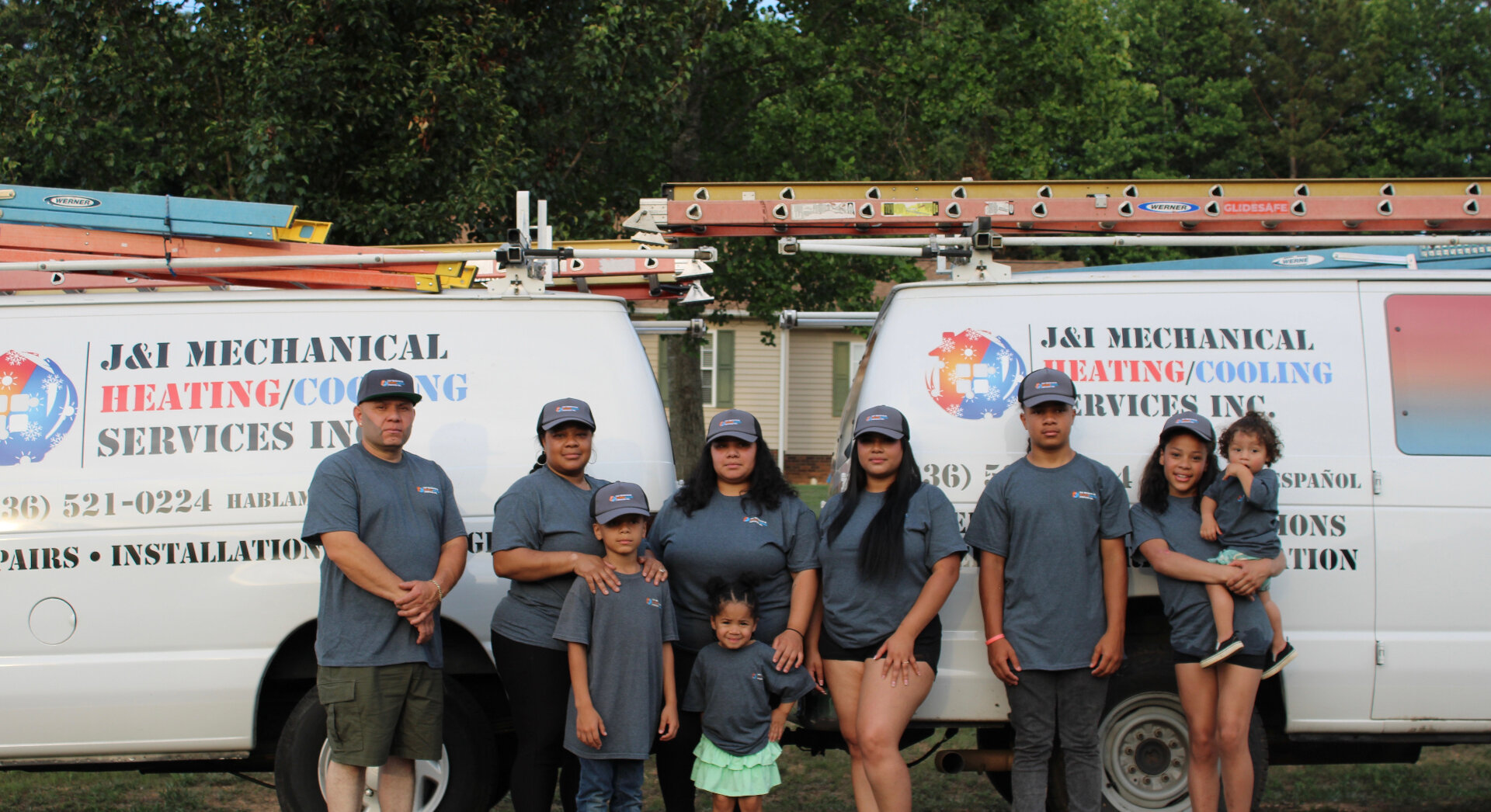 The Benitez family — owners of J&I Mechanical — standing in front of their service vans